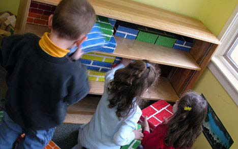photo of three children putting blocks away